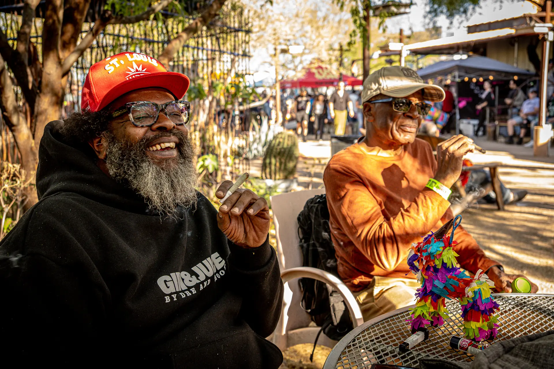 Two friends laughing together outdoors in the sun at a Doobie event.