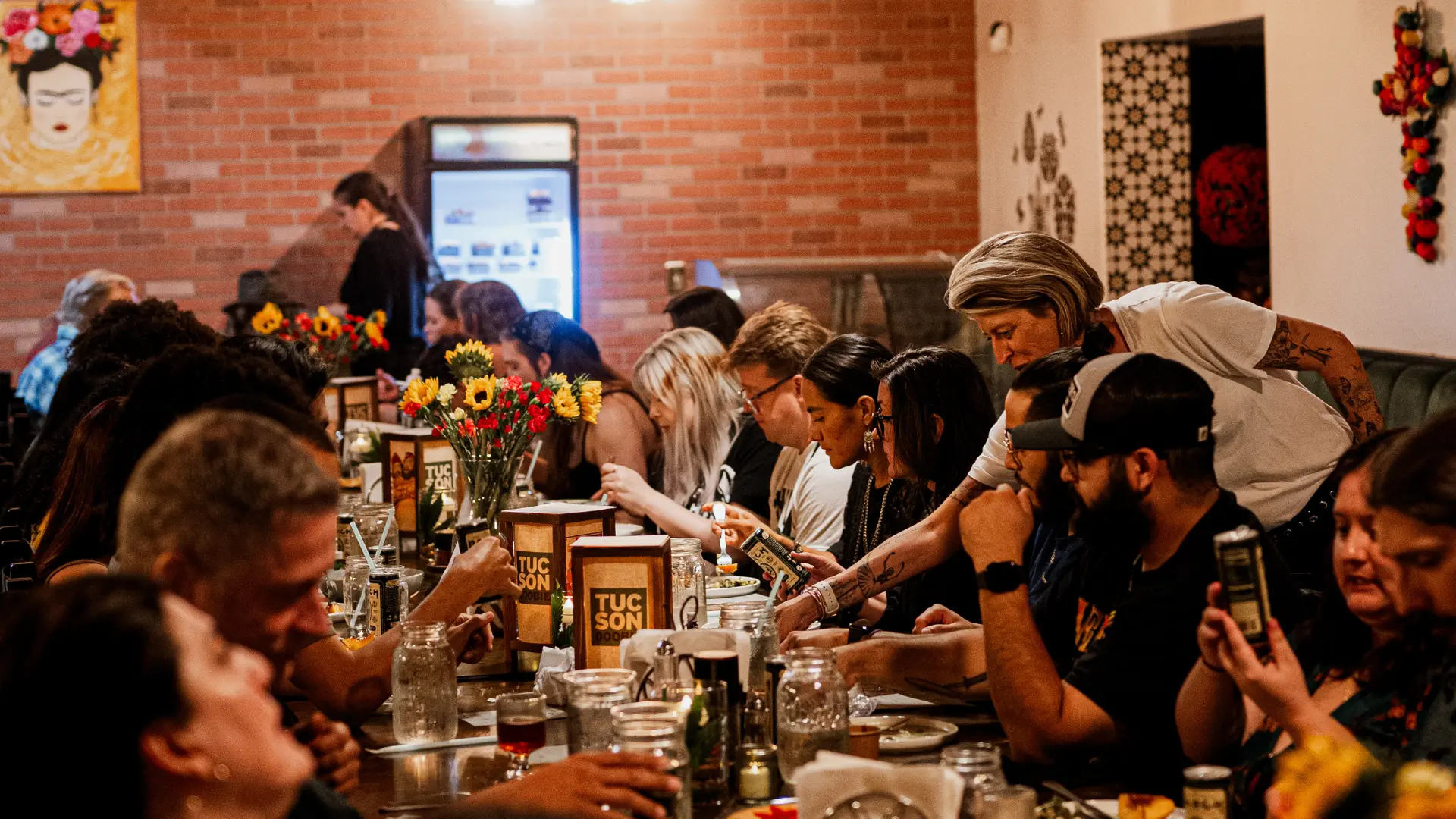 Friends gathered around a long communal dinner table at a Tucson restaurant.